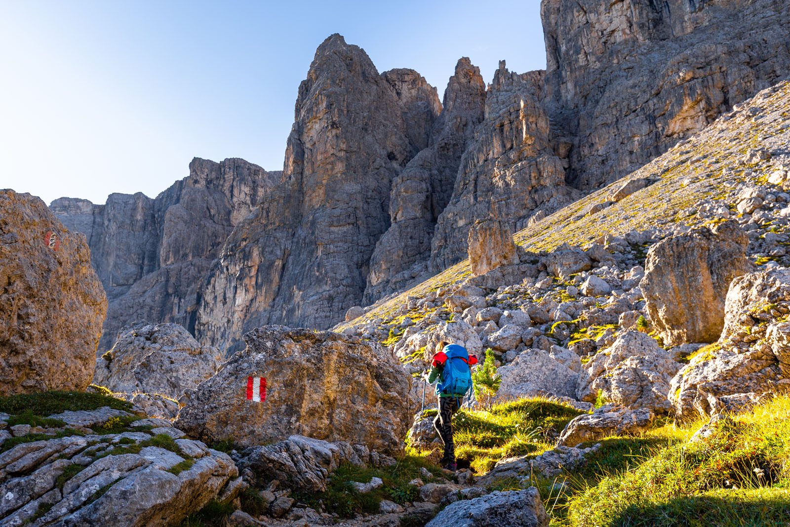 Woman hiking rocky mountain trail under cliffs