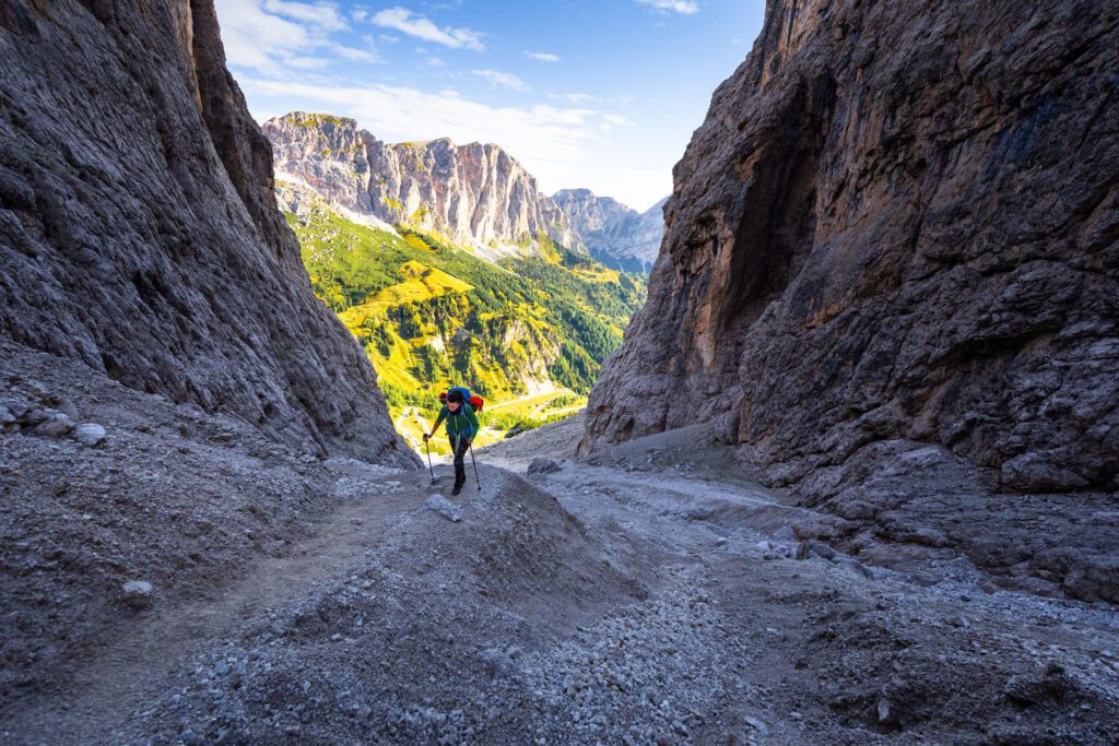 Woman hiking steep rocky mountain trail under cliffs